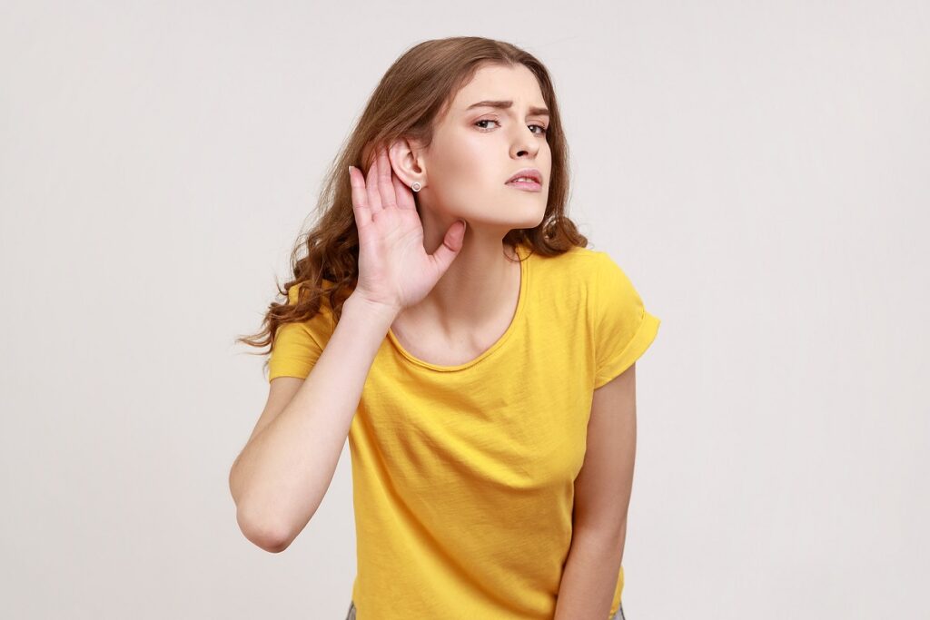 girl who cant hear wearing yellow trying to listen